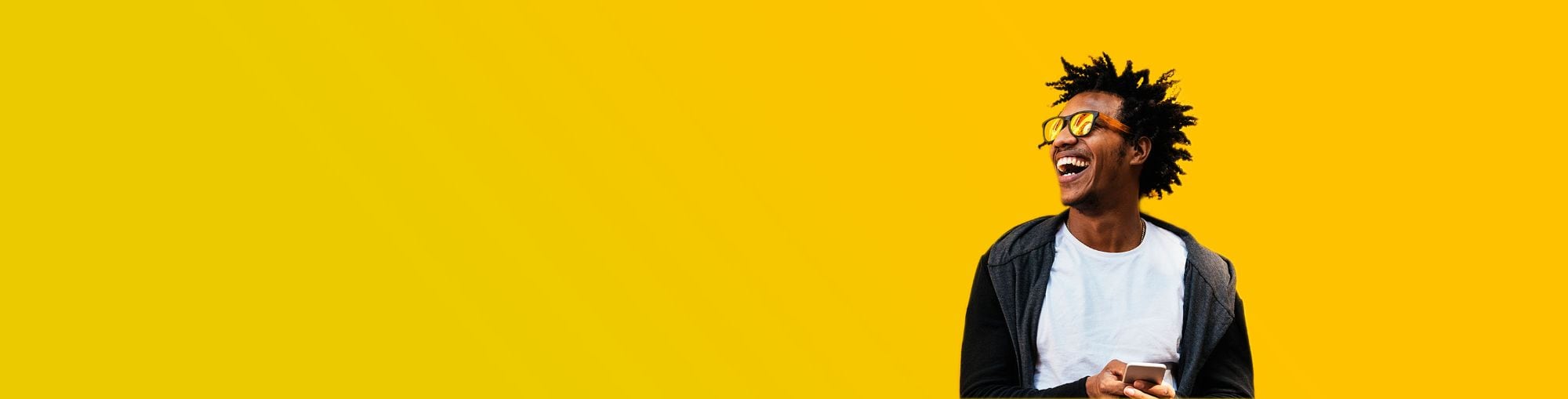 Persona riendo sostiene un teléfono, fondo amarillo vibrante.
