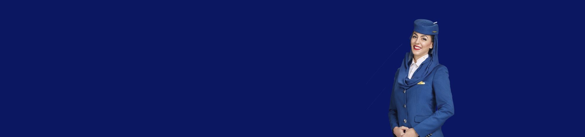 Mujer sonriente, vestida de azafata azul, posa contra un fondo azul liso.