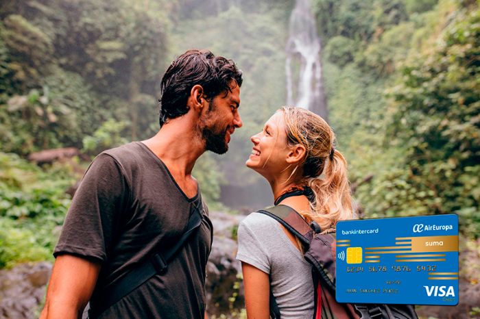 Two people smile at each other in a tropical waterfall; credit card in the foreground.