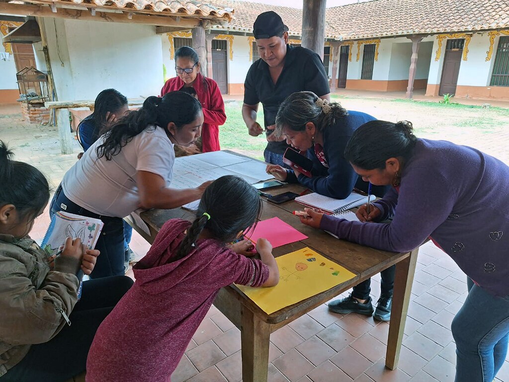 Des enfants dessinent et écrivent ensemble autour d'une table dans la cour de l'école.