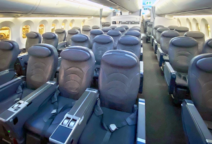 Posti vuoti, allineati in file, all'interno della cabina di un aereo illuminato.